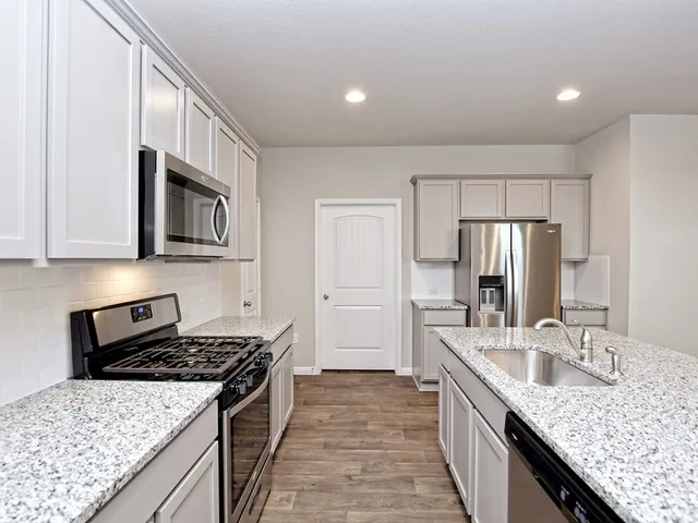 a kitchen with stainless steel appliances granite countertop a sink stove and refrigerator
