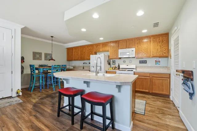 a kitchen with stainless steel appliances kitchen island granite countertop a table chairs sink and cabinets