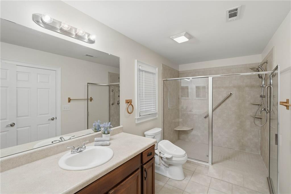 4891 Bill Cheek Road Auburn, GA 30011 - Photo 55 of 99 a bathroom with a granite countertop toilet sink shower and mirror