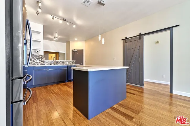 a kitchen with stainless steel appliances kitchen island granite countertop a refrigerator a sink and a dishwasher