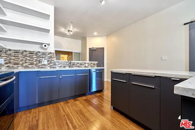 a kitchen with granite countertop a sink cabinets and wooden floor
