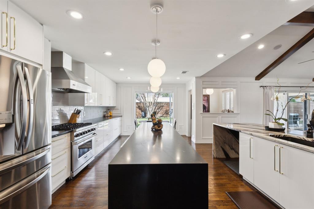 7207 Hunters Ridge Drive Dallas, TX 75248 - Photo 1 of 1 a kitchen with stainless steel appliances a kitchen island hardwood floor sink stove and granite counter top