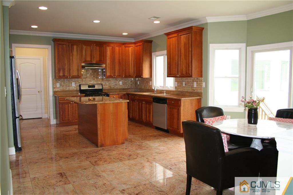 28 Chandler Road Edison, NJ 08820 - Photo 11 of 25 a kitchen with stainless steel appliances granite countertop a stove top oven a sink dishwasher a dining table and chairs with wooden floor
