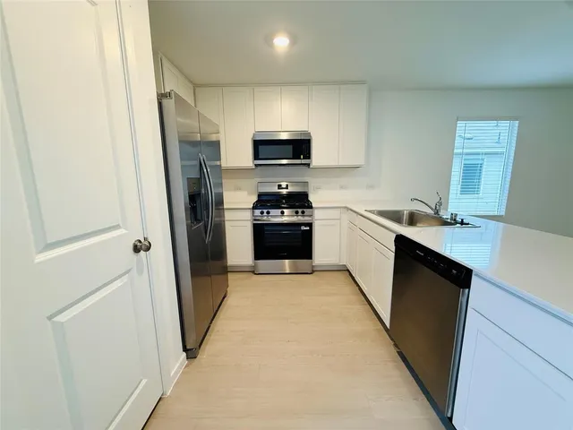 a kitchen with granite countertop a refrigerator stove and sink