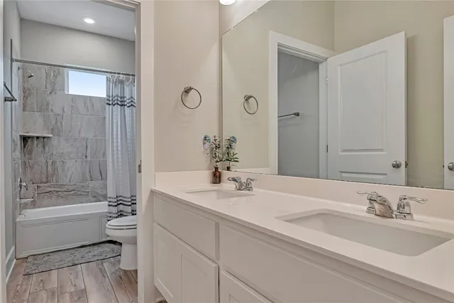 a bathroom with a bathtub shower sink mirror and toilet