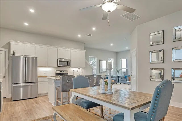 a kitchen with stainless steel appliances granite countertop a refrigerator a stove a sink a dining table and chairs