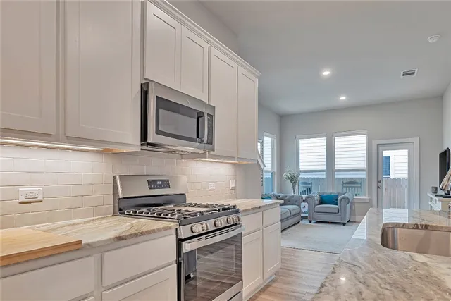 a kitchen with stainless steel appliances granite countertop a stove a sink and a microwave