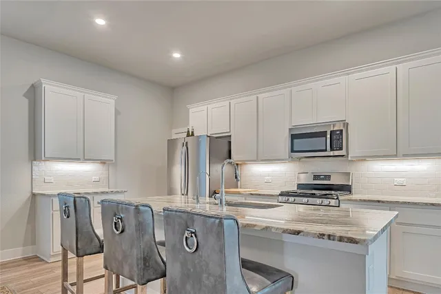 a kitchen with stainless steel appliances granite countertop a stove a sink a microwave a refrigerator and cabinets