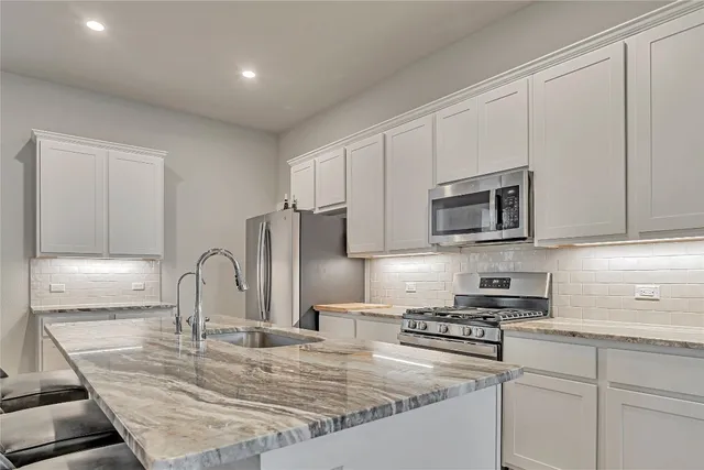 a kitchen with stainless steel appliances granite countertop a stove a sink and a microwave
