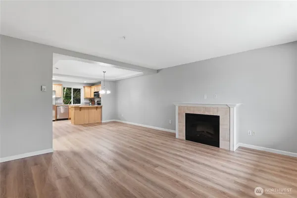 a view of an empty room with a kitchen and fireplace