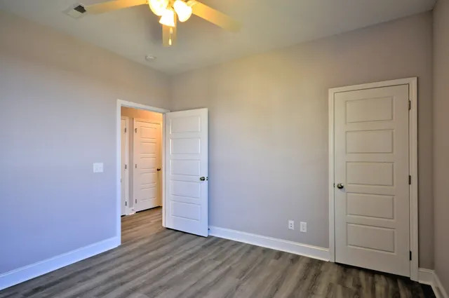 an empty room with wooden floor closet and windows