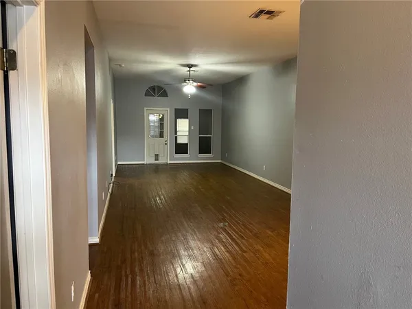 a view of a hallway with wooden floor and a living room