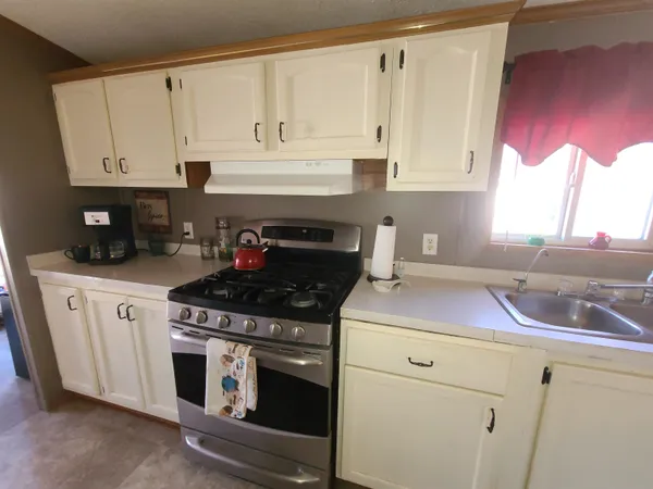 a kitchen with granite countertop a stove sink and cabinets