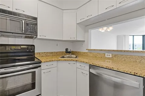 a kitchen with granite countertop a stove sink and cabinets