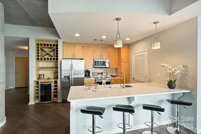 a kitchen with stainless steel appliances kitchen island granite countertop a kitchen island and chairs in it