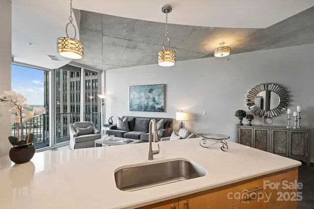 a kitchen with a sink a counter top space and living room view