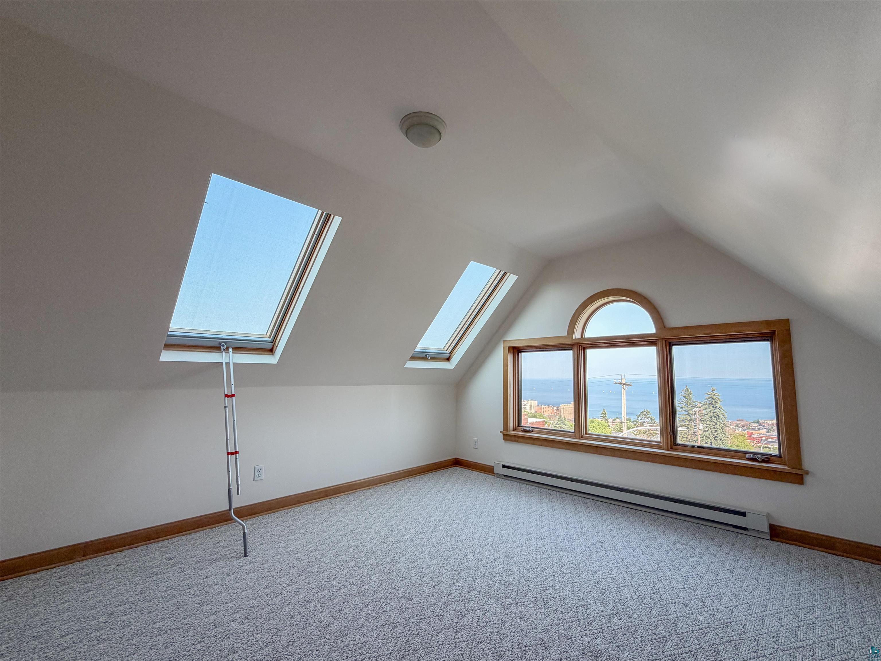 13 West 8th Street Duluth, MN 55806 - Photo 32 of 57 Attic room featuring two skylights, a three-panel window with an arched transom, and wood-finish trim