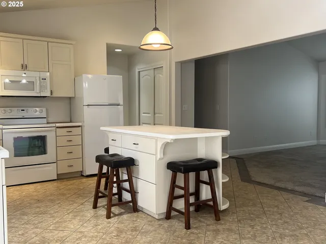a kitchen with stainless steel appliances kitchen island a table chairs in it and white cabinets