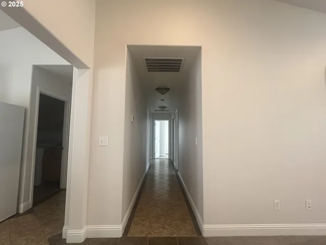 a view of a hallway with wooden floor and a window