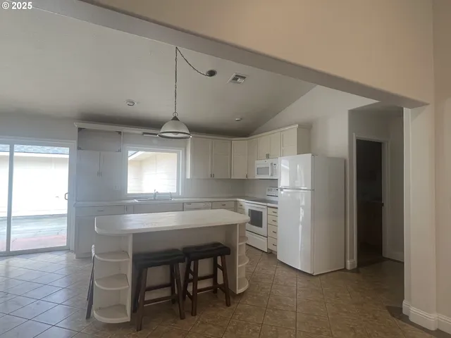 a kitchen with a refrigerator a sink dishwasher with a dining table and chairs