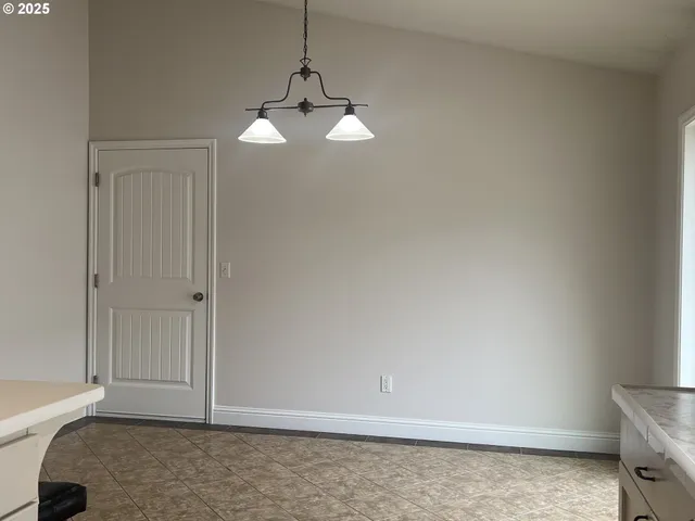 a view of an empty room and chandelier fan