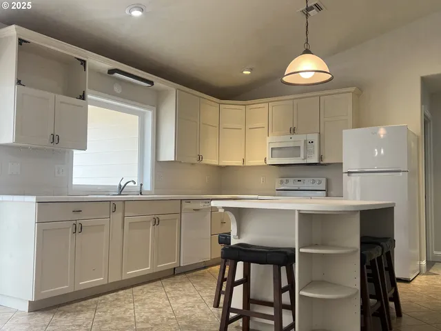 a kitchen with kitchen island white cabinets and white appliances