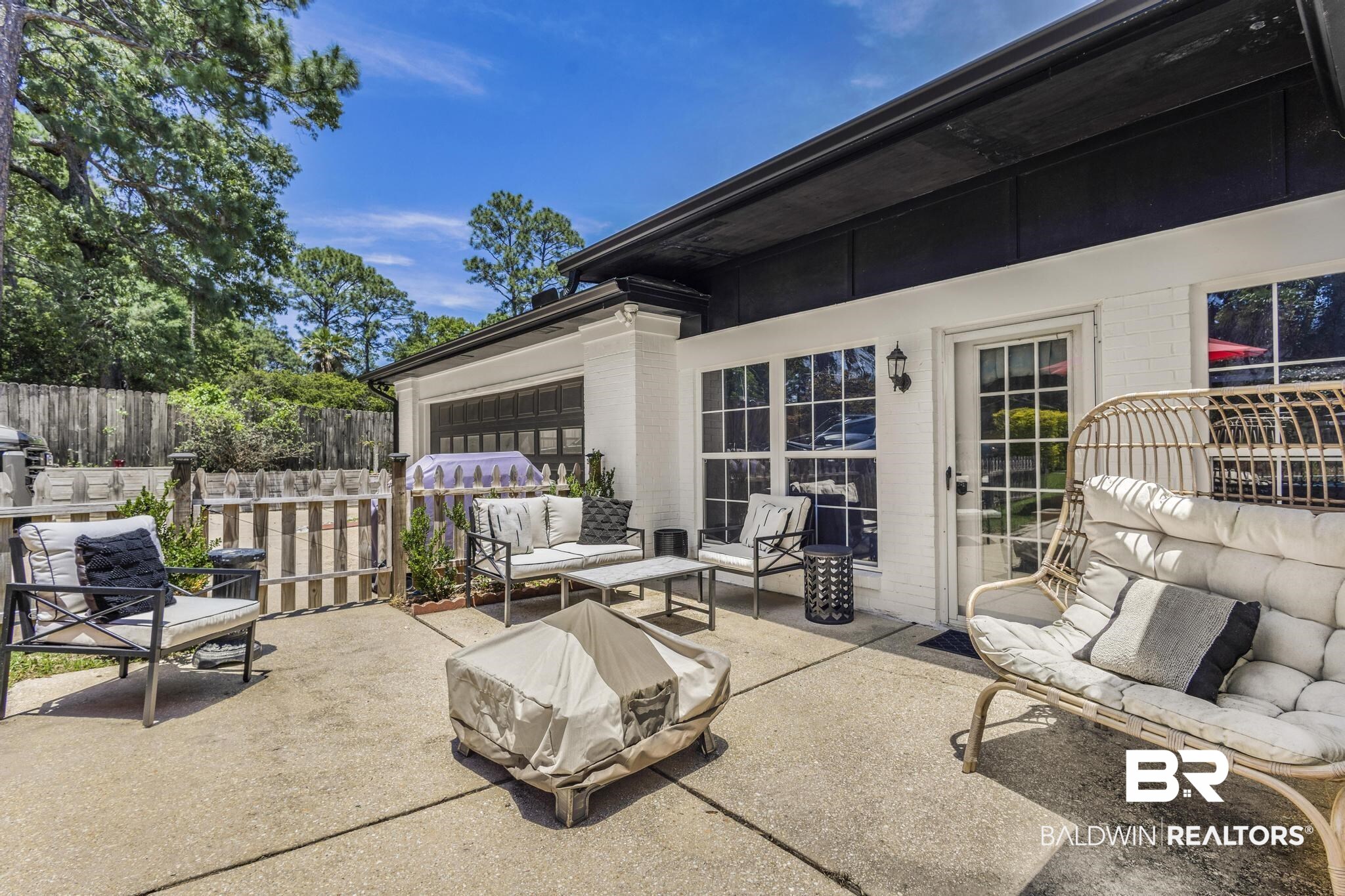 83 Caisson Trace Daphne, AL 36527 - Photo 56 of 63 Expansive concrete patio with white brick exterior, black trim, multiple windows, and a glass-paneled door