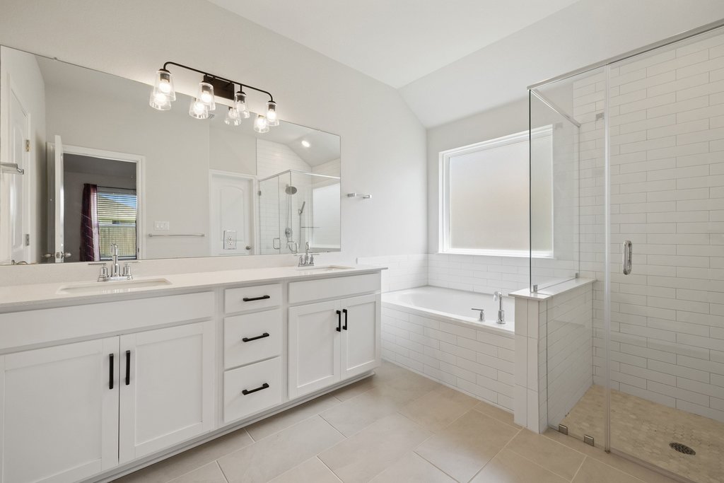 105 Cupa Monti Road Hutto, TX 78634 - Photo 16 of 28 Full bath featuring double vanity, lofted ceiling, a shower stall, a bath, and light tile patterned floors