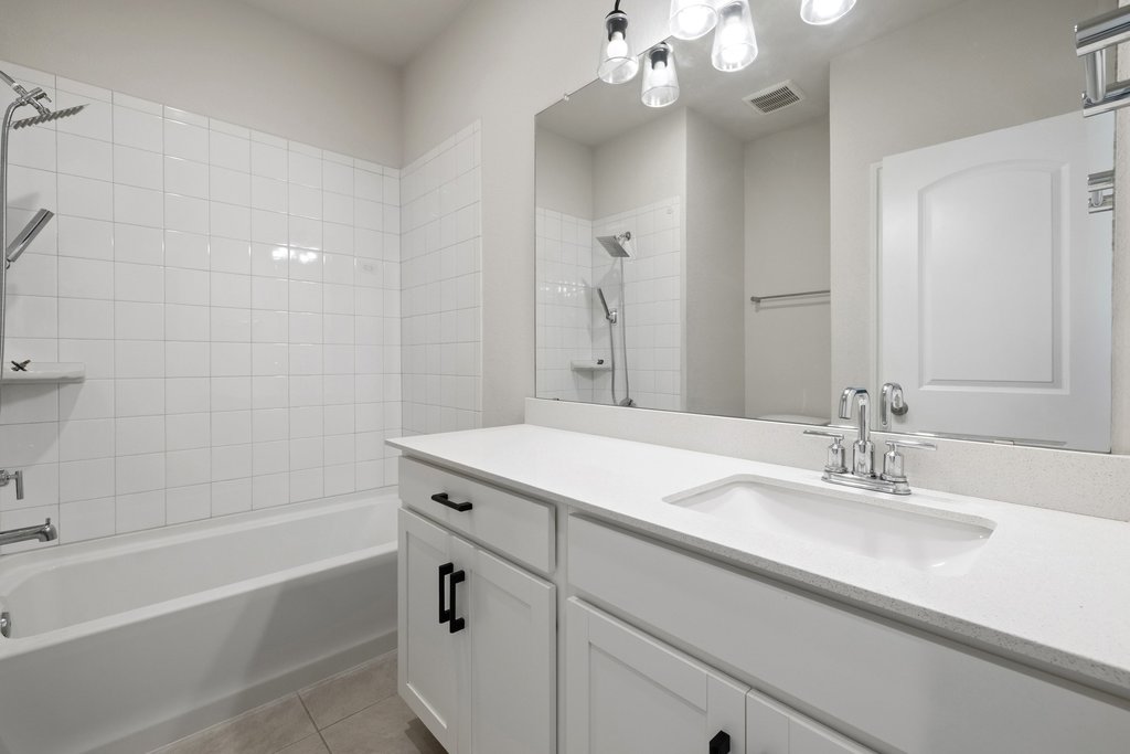 105 Cupa Monti Road Hutto, TX 78634 - Photo 19 of 28 Bathroom with vanity, tiled shower / bath combo, and light tile patterned floors
