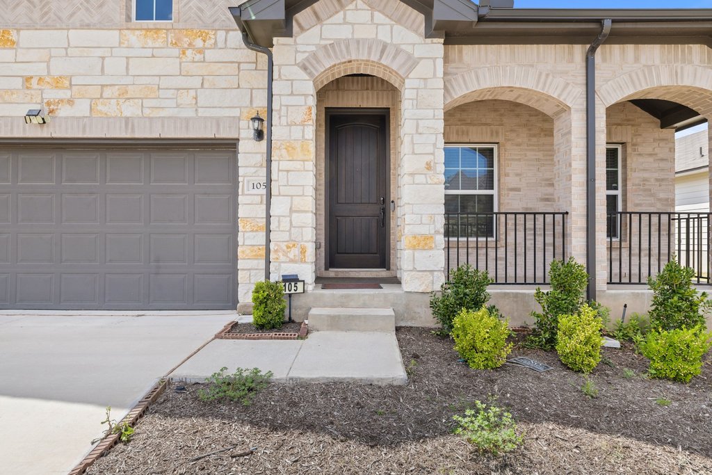 105 Cupa Monti Road Hutto, TX 78634 - Photo 2 of 28 Doorway to property featuring stone siding, a porch, a garage, and driveway