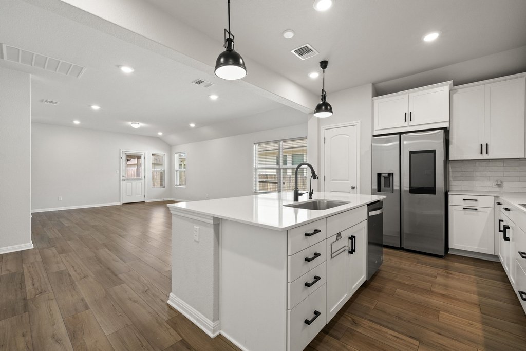 105 Cupa Monti Road Hutto, TX 78634 - Photo 5 of 28 Kitchen with white cabinetry, a kitchen island with sink, stainless steel appliances, and dark wood-style floors