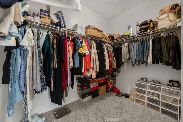 a view of walk in closet with clothes and shoes