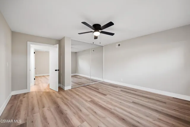 a view of empty room with wooden floor and fan