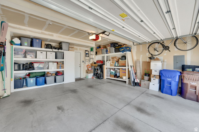 7713 Navarro View Court Midvale, UT 84047 - Photo 25 of 41 Spacious garage with exposed beam ceiling, concrete flooring, built-in shelving, a side door entry, and an automatic garage door opener