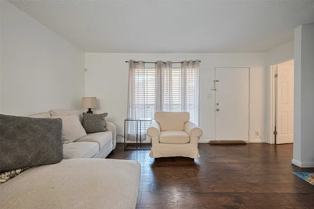 a living room with couches and a potted plant on table with wooden floor