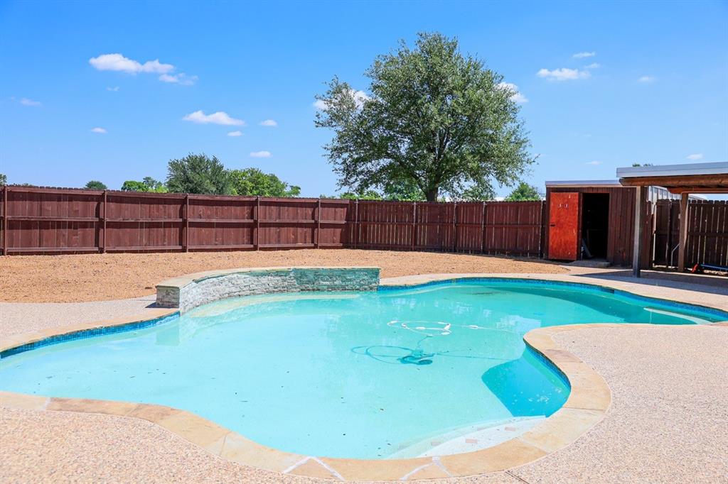 10575 Friendship Road Pilot Point, TX 76258 - Photo 26 of 32 Curved swimming pool with stone coping and an integrated raised spa area