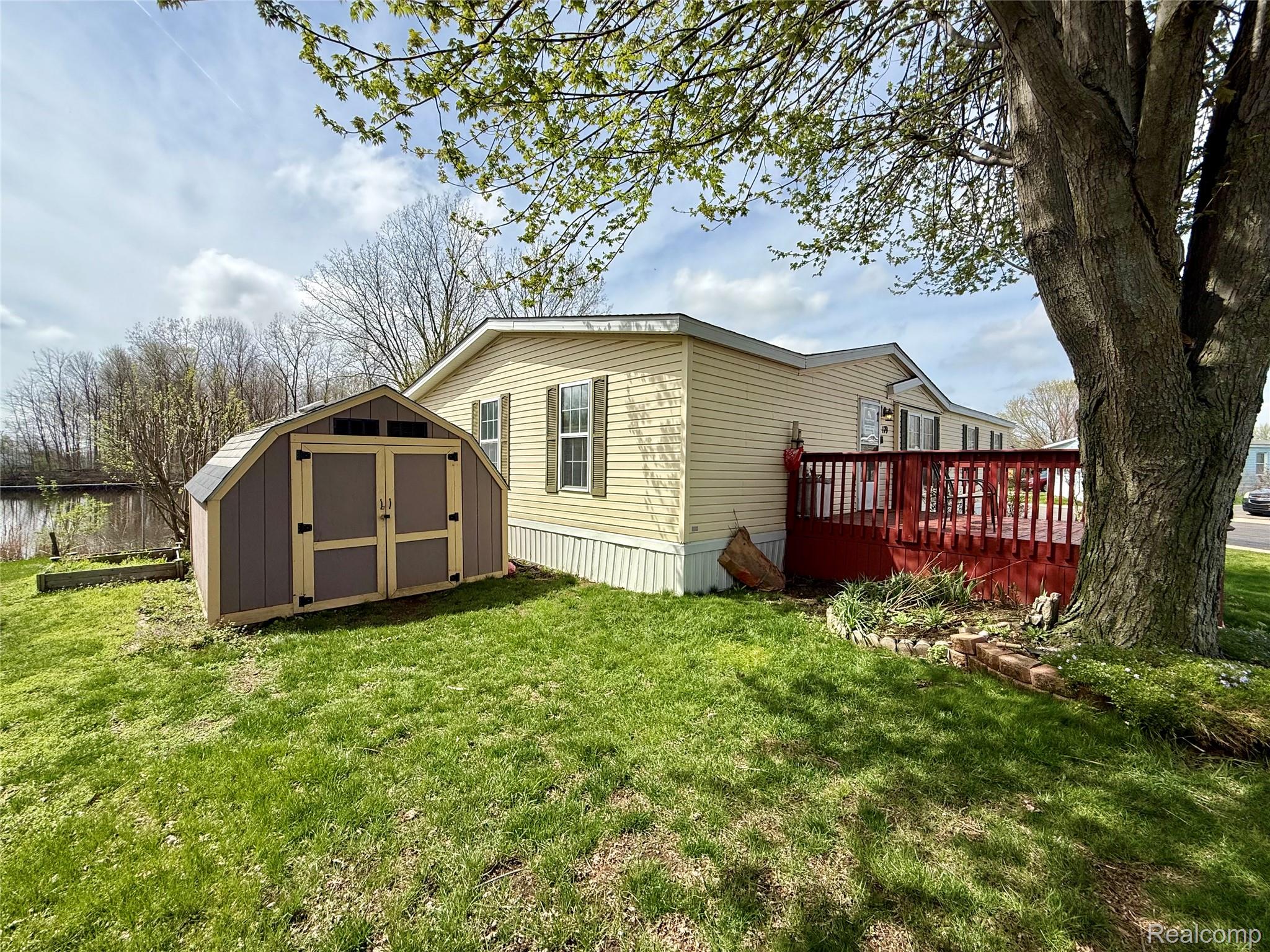 6988 McKean Road Ypsilanti, MI 48197 - Photo 20 of 21 View of home's exterior featuring a storage shed, a deck, and a lawn