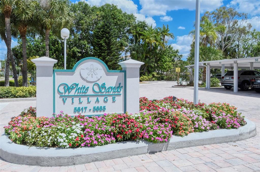 5641 Midnight Pass Road, Unit 904 Sarasota, FL 34242 - Photo 14 of 24 a sign that is in front of flowers