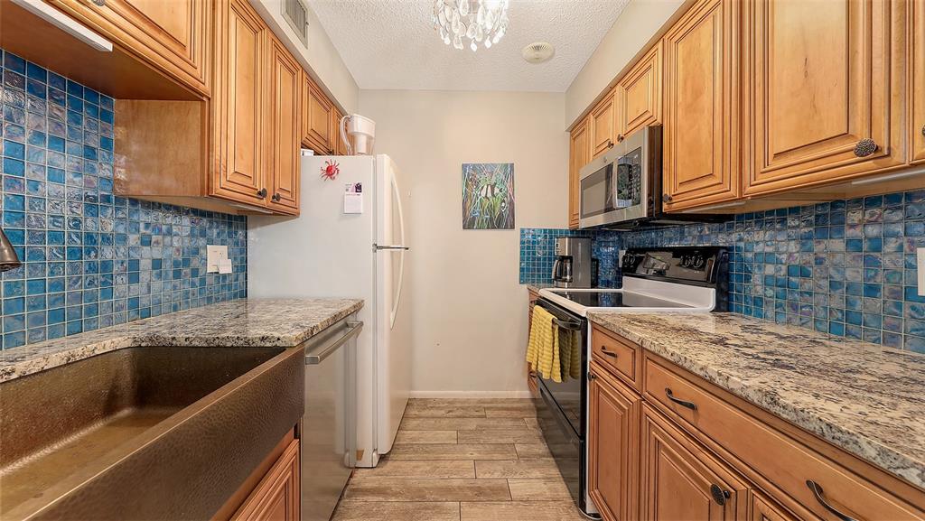 5641 Midnight Pass Road, Unit 904 Sarasota, FL 34242 - Photo 9 of 24 a kitchen with stainless steel appliances granite countertop a sink a stove and a refrigerator