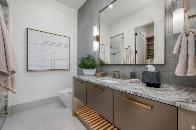 2867 East Granite Way St. George, UT 84790 - Photo 49 of 69 Bathroom vanity featuring a natural stone countertop with integrated sink, bronze-finish fixtures, and a large framed mirror