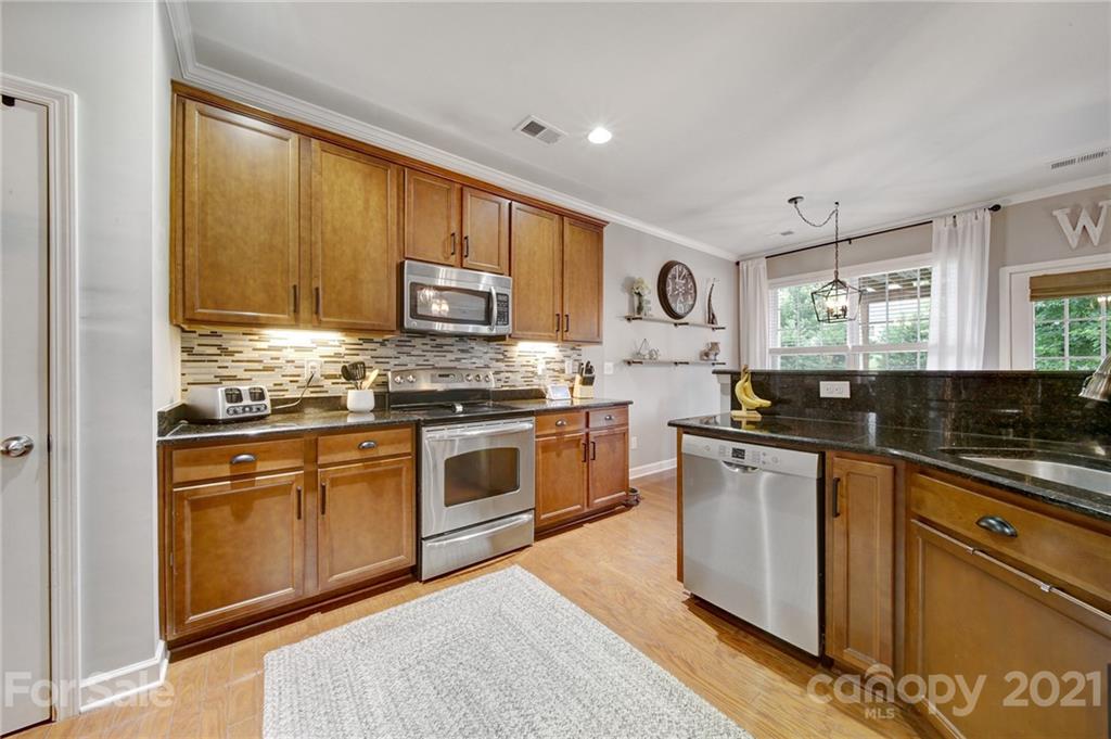 823 Solandra Way Tega Cay, SC 29708 - Photo 12 of 43 a kitchen with stainless steel appliances granite countertop a stove a sink dishwasher and a microwave oven with cabinets