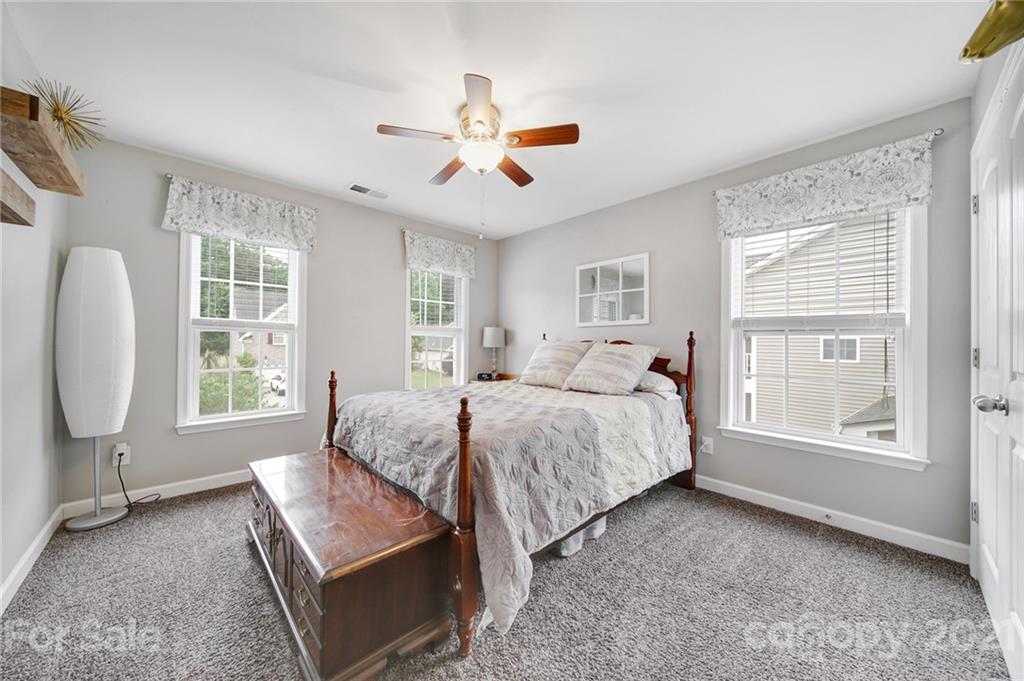 823 Solandra Way Tega Cay, SC 29708 - Photo 36 of 43 a spacious bedroom with a bed a chandelier and a window