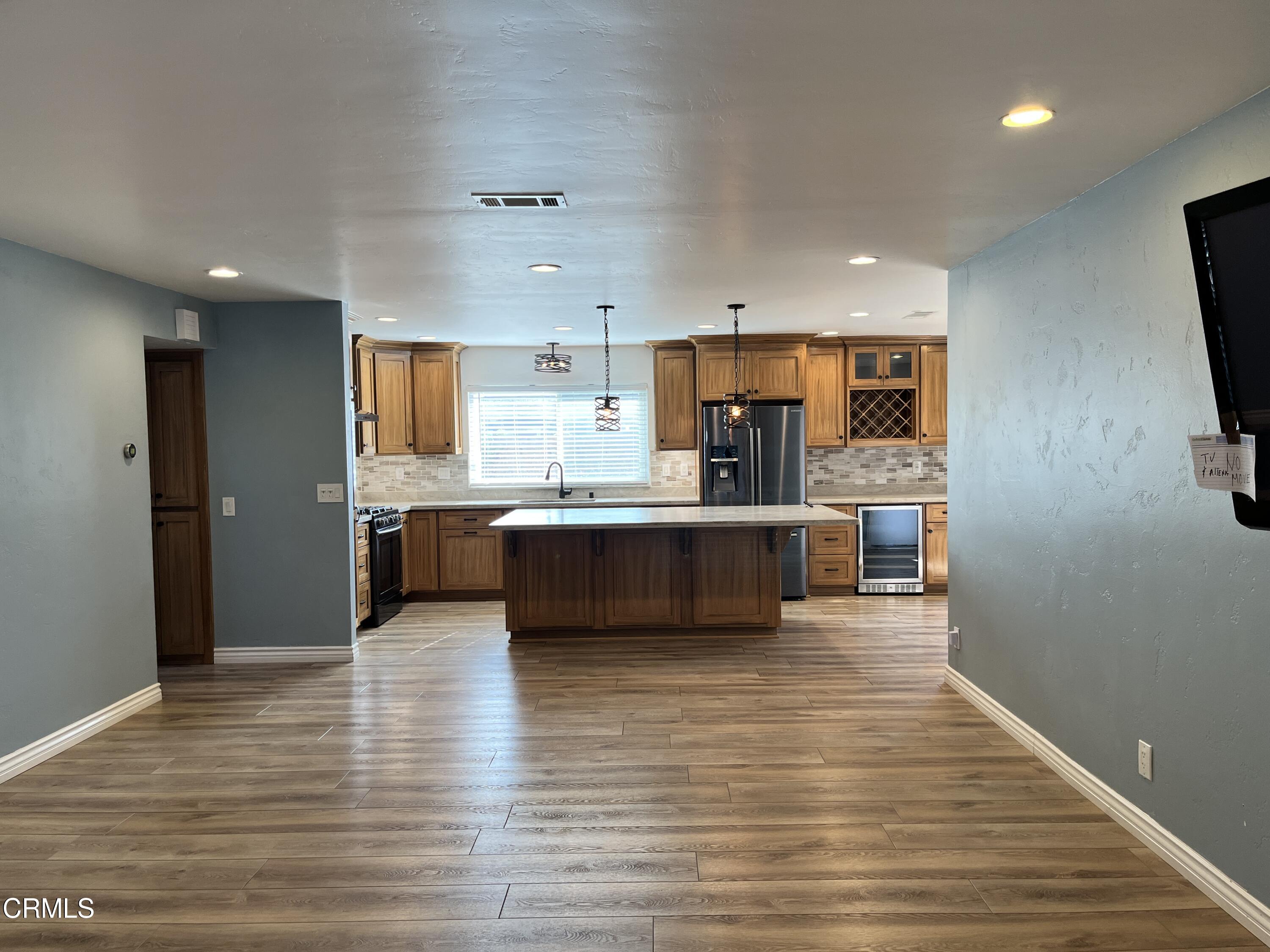 3540 Regatta Place Oxnard, CA 93035 - Photo 2 of 17 a view of a kitchen with kitchen island a sink wooden floor and a counter top space