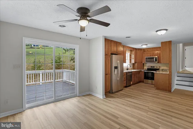 a view of kitchen with stainless steel appliances wooden floor and window
