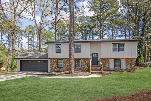 a view of a house with backyard and a tree