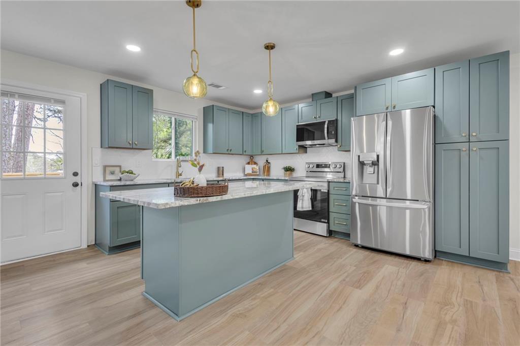 6788 Collier Way Riverdale, GA 30296 - Photo 8 of 37 a kitchen with stainless steel appliances granite countertop a refrigerator a sink dishwasher a stove and white cabinets with wooden floor