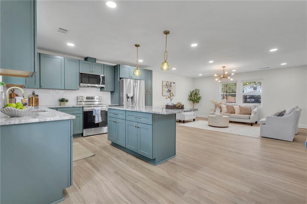 6788 Collier Way Riverdale, GA 30296 - Photo 10 of 37 a large kitchen with kitchen island a sink a center island stainless steel appliances and a fireplace