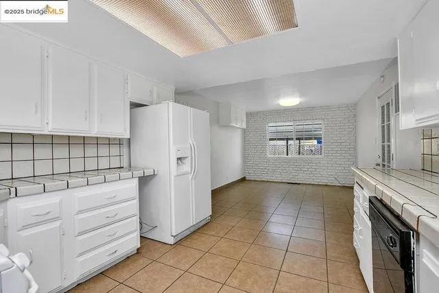 a kitchen with white cabinets and refrigerator
