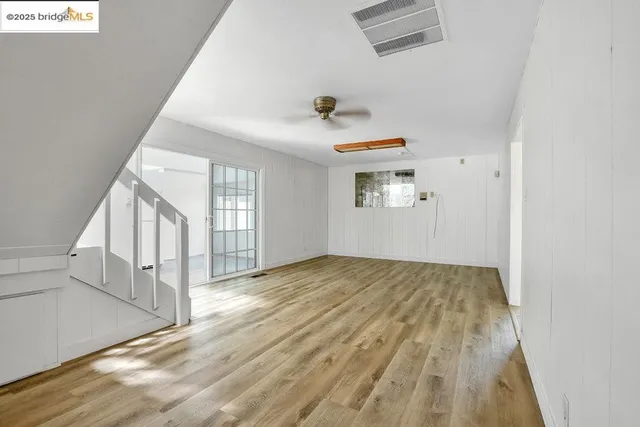 a view of empty room with wooden floor and fan