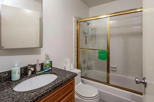 a bathroom with a granite countertop sink toilet a mirror and shower